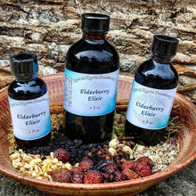 Load image into Gallery viewer, Elderberry Elixir Syrup with raw honey and honeysuckle in a 2 oz. bottle, featuring wildcrafted ingredients like elderberry and mullein.