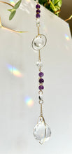 Load image into Gallery viewer, Gift for crystal lovers: Amethyst and Citrine dual prism suncatcher with gold circle frames and rainbow reflections
