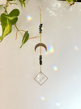 Load image into Gallery viewer, Half moon suncatcher shown at an angle highlighting gold charm, beads, and prism reflections
